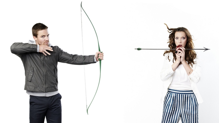 Man with bow and arrow aims at woman holding apple