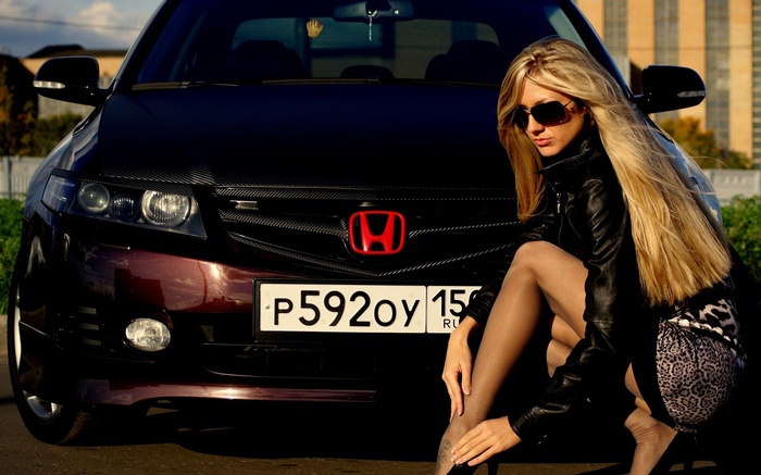 Woman in leather jacket and leopard print skirt posing by Honda car