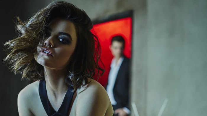 Lucy Hale in a dark setting with a man in the background