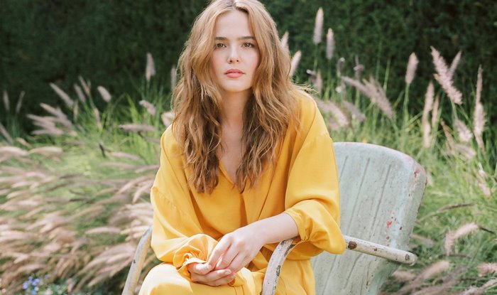 Zoey Deutch sitting in a chair outdoors