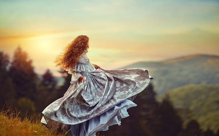 Woman in a flowing dress on a grassy hill