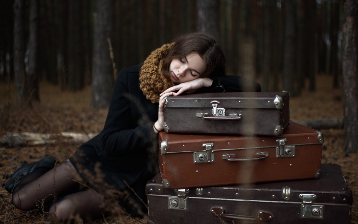 Woman sleeping on suitcases in a forest