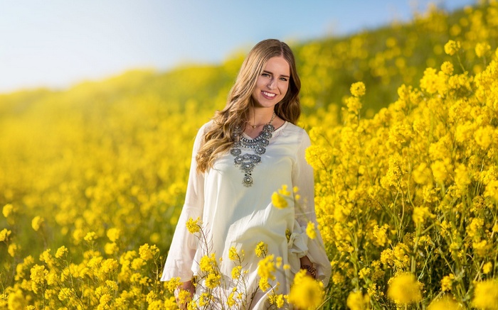 Woman in white dress in a field of yellow flowers