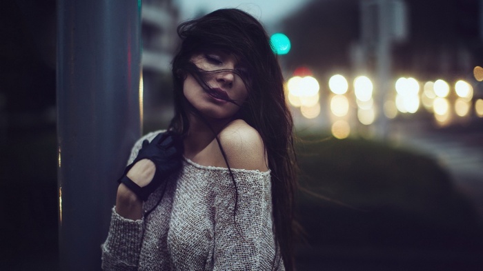 Woman with dark hair and black gloves at night