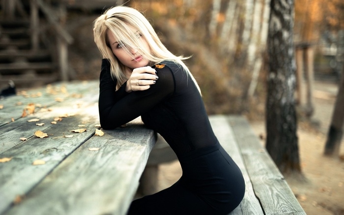 Woman in black dress sitting at a wooden table