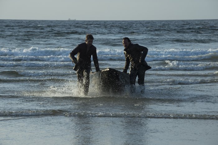 Jerome Flynn carrying a large object on a beach