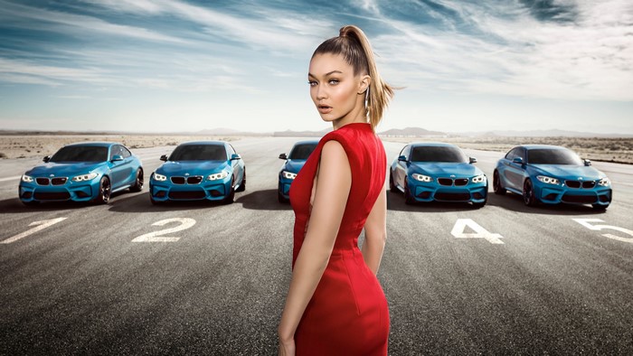 Gigi Hadid with BMW M2 cars on a racetrack