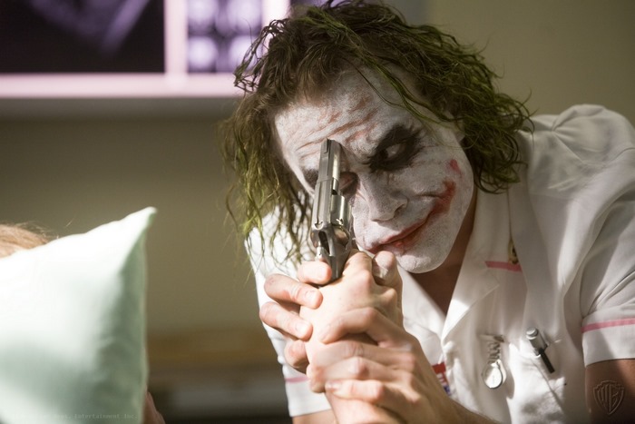 Heath Ledger as the Joker holding a gun