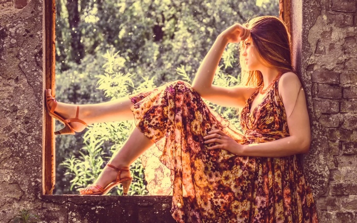 Woman in floral dress sitting in a window frame