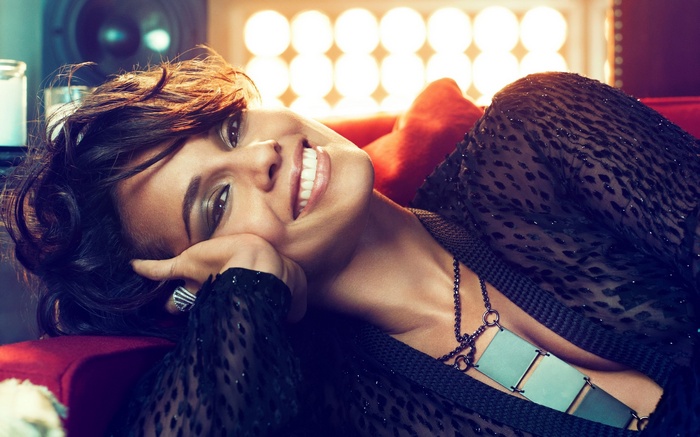 Woman with dark hair lying on a red couch