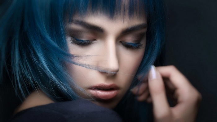 Woman with blue hair looking down