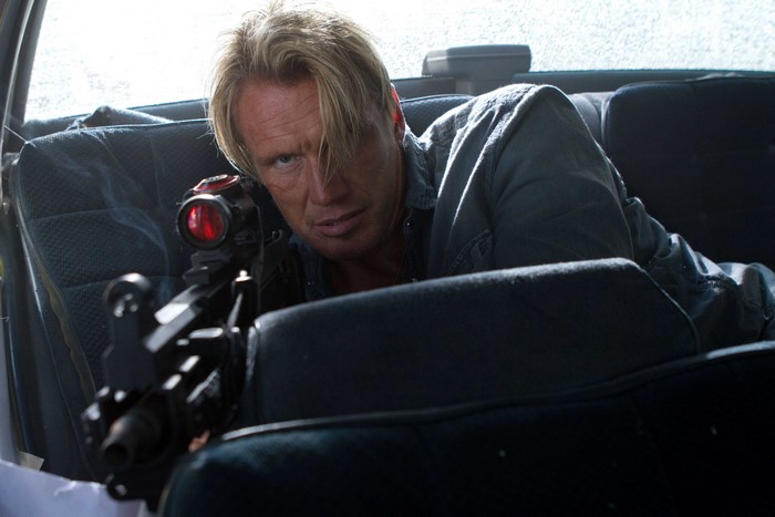 Dolph Lundgren with a rifle in a car