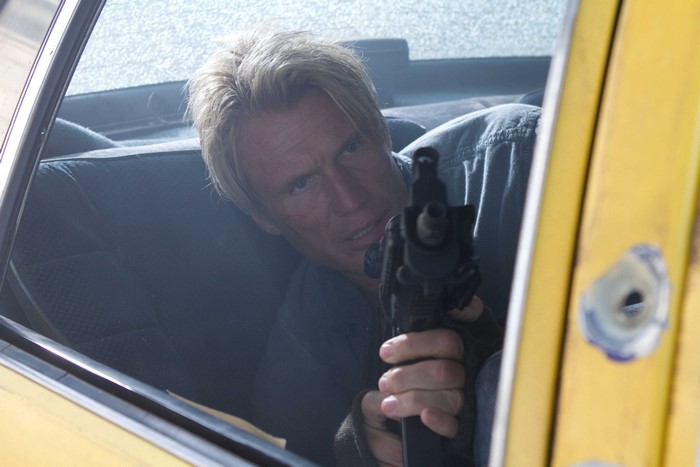 Dolph Lundgren aiming a gun from a car