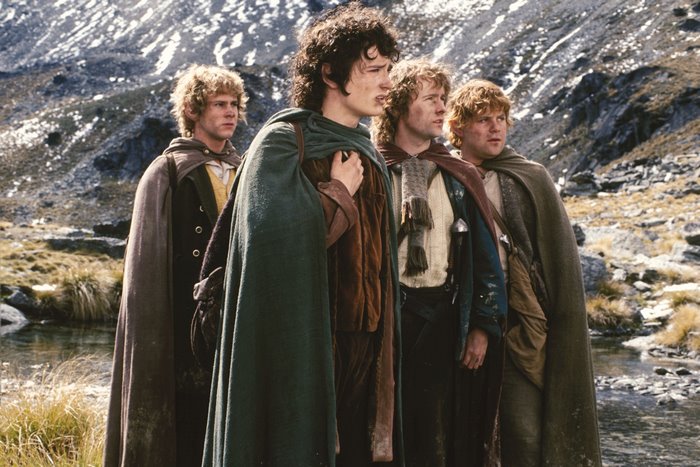 Four hobbits from The Lord of the Rings in a mountainous landscape