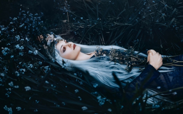 Woman with white hair lying in dark flowers