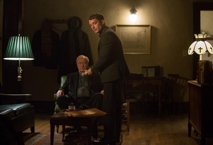 Elijah Wood and Michael Caine in a dimly lit room