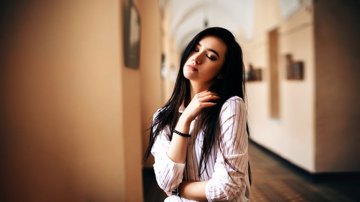 Woman with eyes closed in a hallway