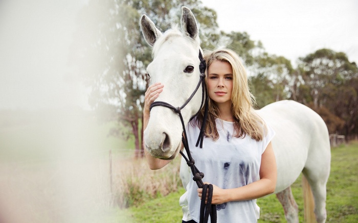 Woman with white horse in a field