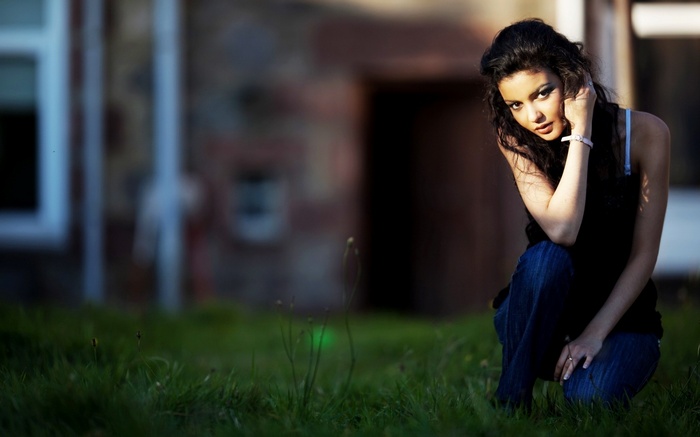 Woman crouching in grass near building
