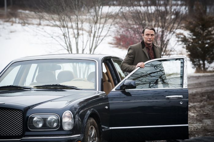 Mads Mikkelsen standing by a Bentley
