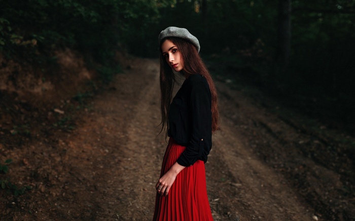 Woman in red skirt and beret in forest