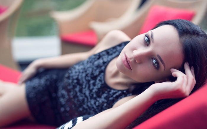Woman in a sequined dress lying on a red surface