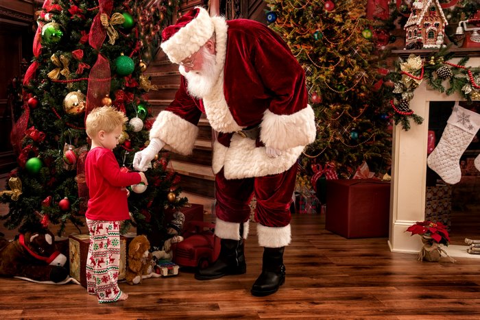 Santa Claus and a young boy decorating a Christmas tree
