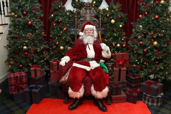 Santa Claus sitting on a throne with Christmas trees