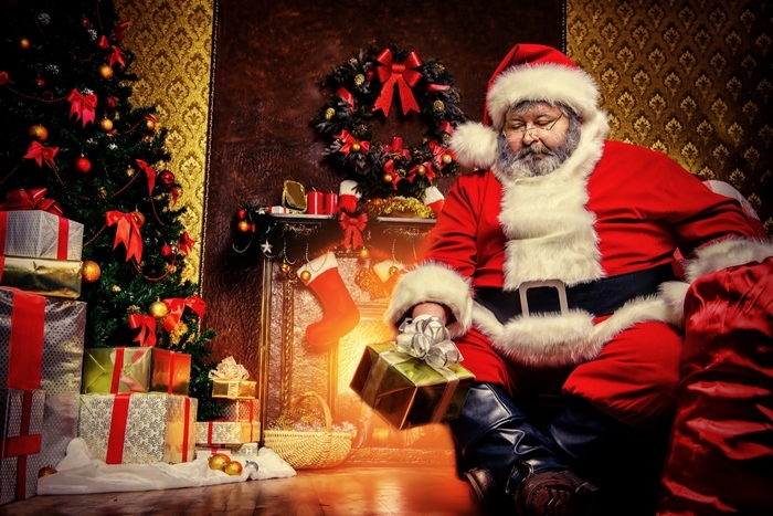 Santa Claus with gifts by a Christmas tree