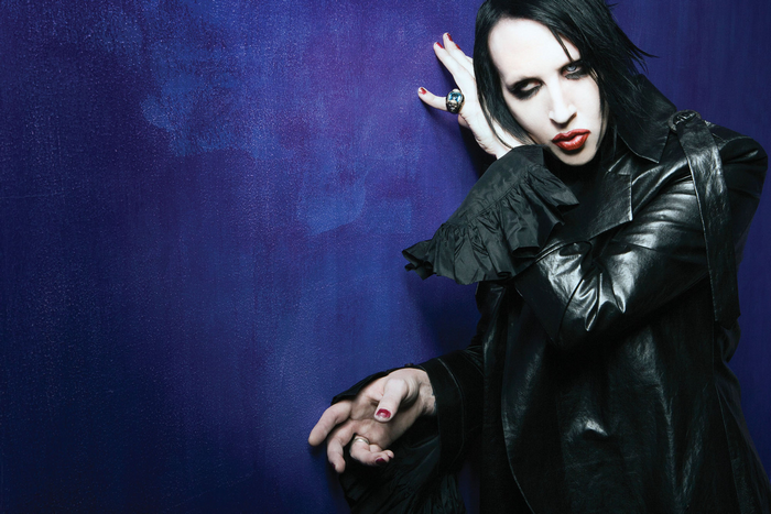 Marilyn Manson leaning against a purple wall