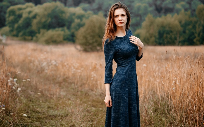 Woman in a dark blue dress standing in a field