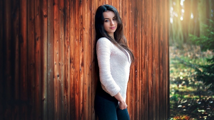 Woman leaning against a wooden wall in a forest