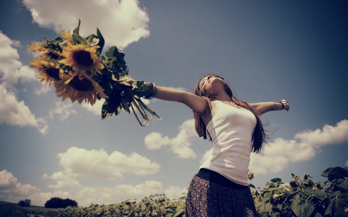Woman holding sunflowers in a field