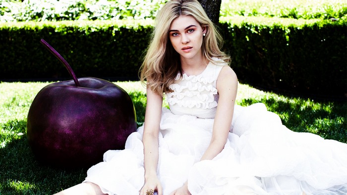 Nicola Peltz in a white dress with a giant cherry