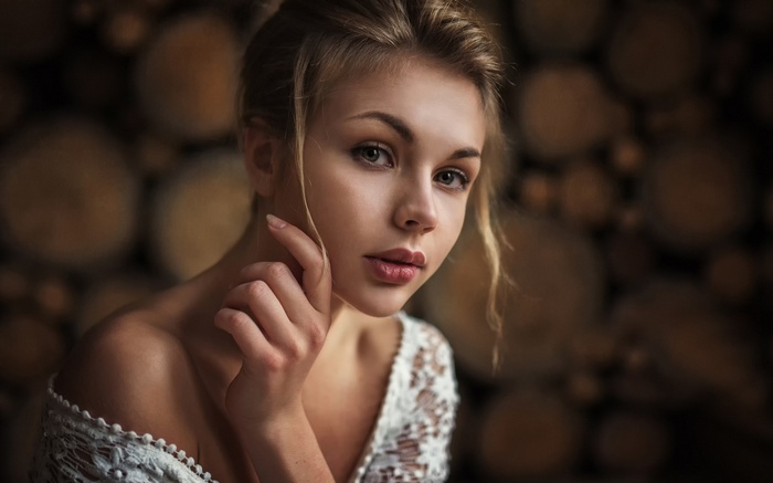 Woman in white lace top with hand on chin