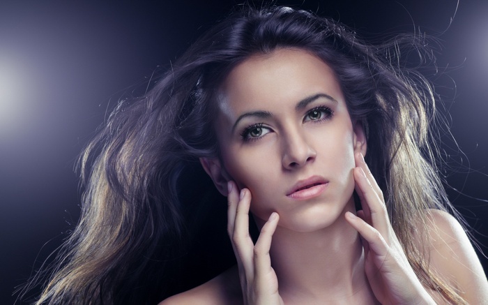 Woman with flowing hair and hands on face