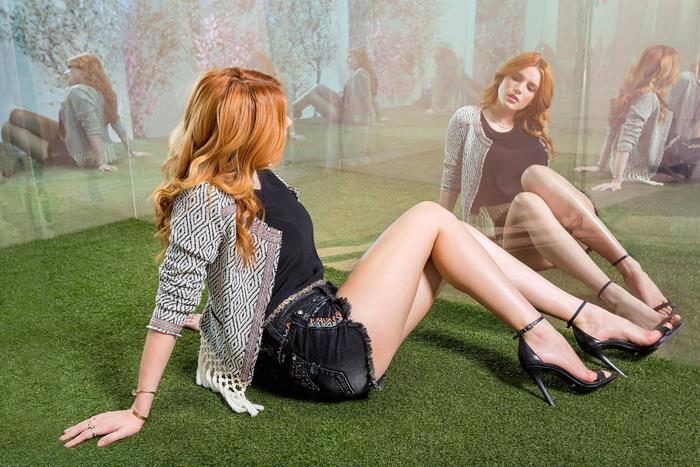 Bella Thorne sitting on grass with reflections