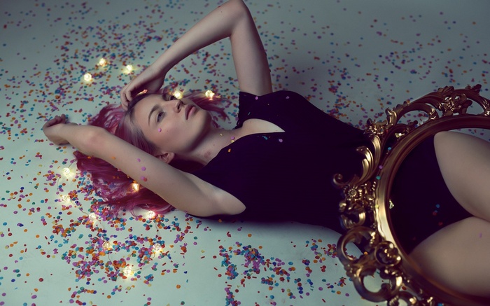 Woman with pink hair lying on confetti