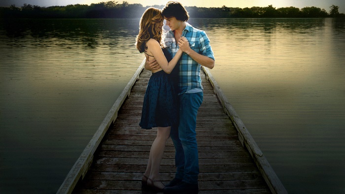 Couple dancing on a wooden pier at sunset
