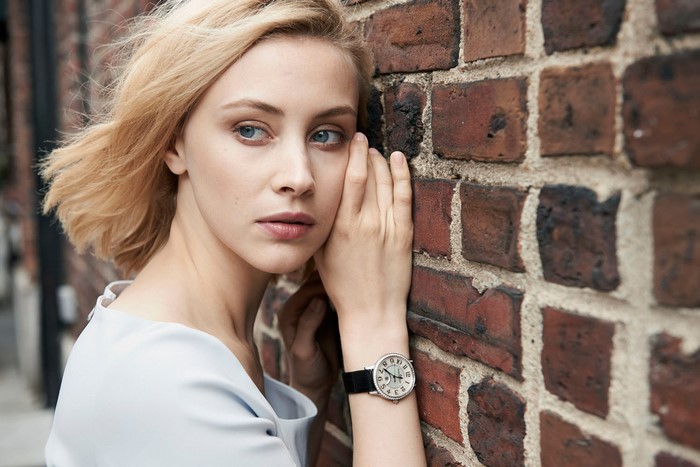 Sarah Gadon leaning against a brick wall