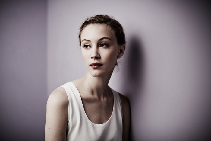 Sarah Gadon leaning against a purple wall