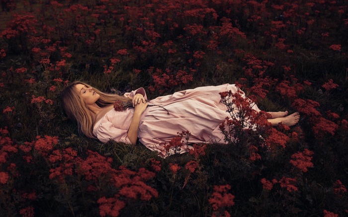 Woman lying in a field of red flowers