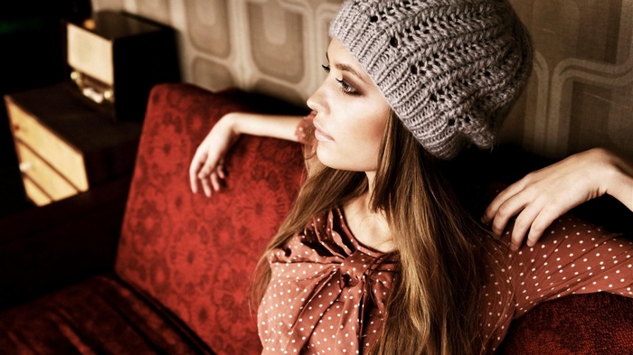Woman in a knitted hat sitting on a red couch