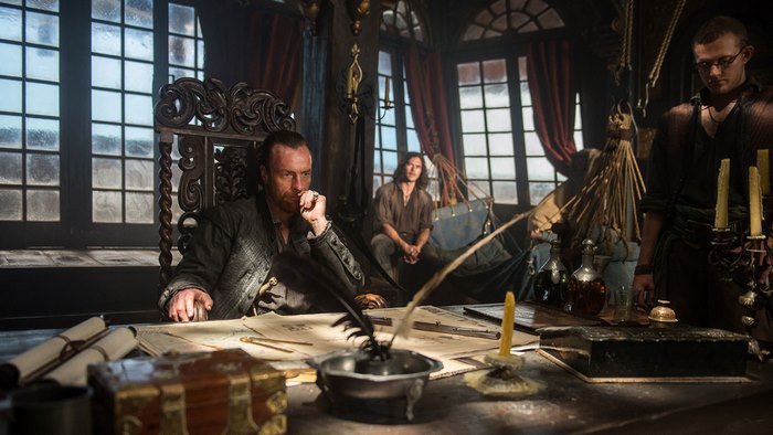 Toby Stephens in a dimly lit room with maps