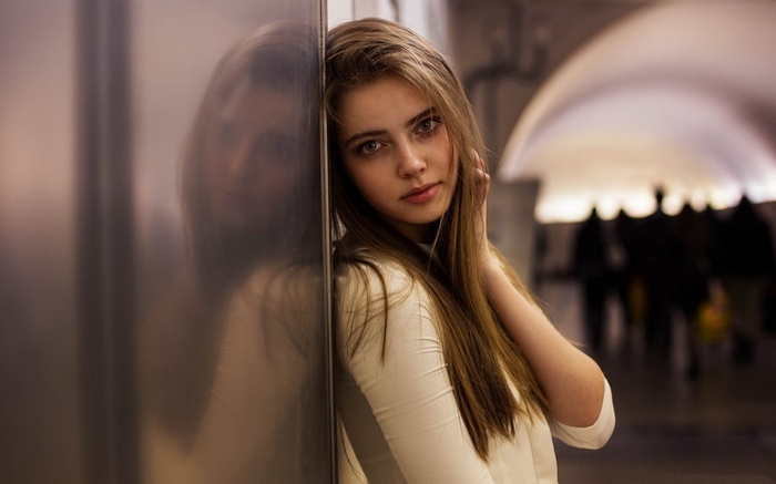 Young woman leaning against a wall in a subway station