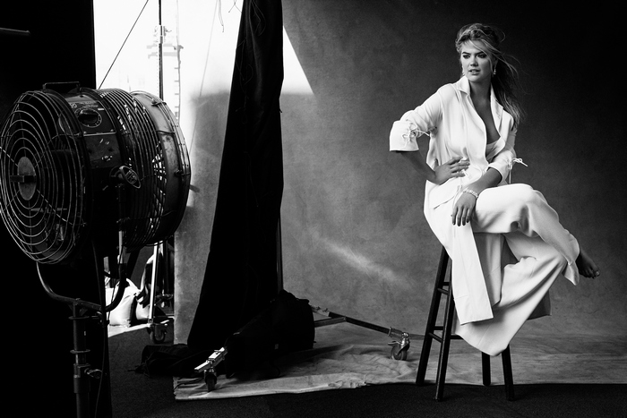 Kate Upton in white suit sitting on stool