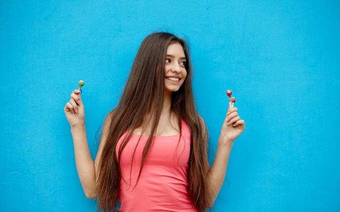Girl with lollipops against blue wall