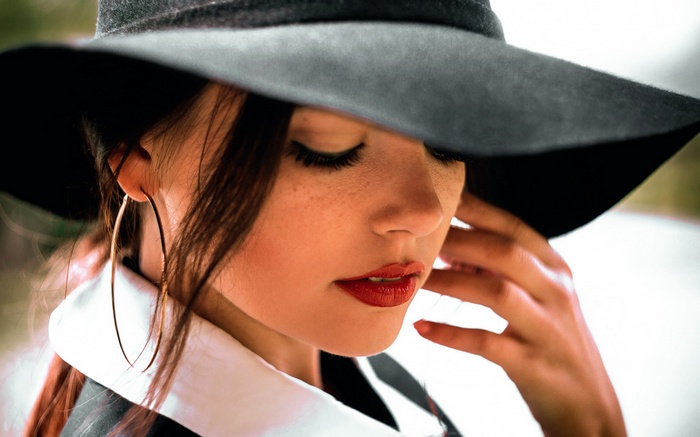 Woman in a wide-brimmed hat and hoop earrings