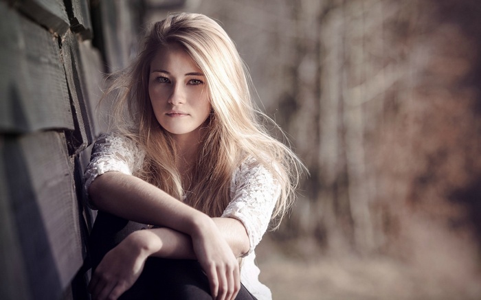 Young woman with blonde hair sitting outdoors
