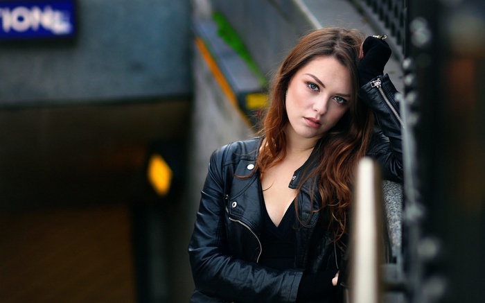 Woman in leather jacket leaning against railing